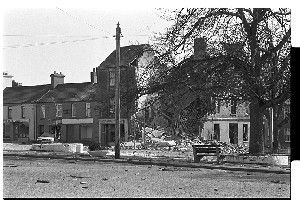 Massive PIRA explosion in Castlewellan, Co. Down. The large bomb was detonated as a British soldier walked past the shop. He was killed and the shop destroyed. Photos taken shortly after the blast and show damage to shop and British Army at the scene