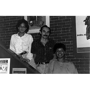 Members of Inquilinos Boricuas en Acción's administrative staff pose for a photograph on the stairs beside an interior exposed brick wall.