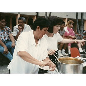 Women serving food at an outdoor community event.