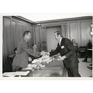 Richard Harte, Jr., at left, presents an award to John Whelam and shakes his hand at a Boys' Club meeting