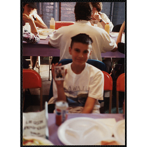 A boy sitting at a table displays a photograph at a Boys and Girls Club Awards Night