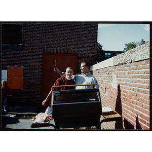 A girl and a man pose behind a grill at a carnival