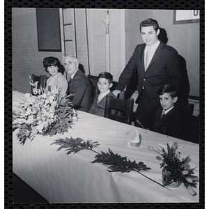 Two boys pose with two men and a woman at the head table during a Dad's Club/Mother's Club banquet