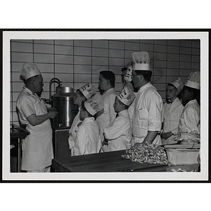 A cook addresses members of the Tom Pappas Chefs' Club in a kitchen