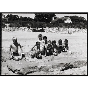 A group of children pose for a group shot on a beach