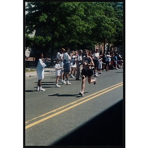 A woman is cheered on by spectators as she runs the Battle of Bunker Hill Road Race