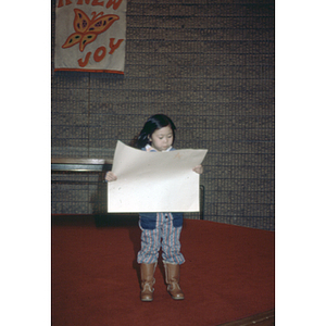 Young girl looks at a poster she has created at a Chinese Progressive Association Christmas party