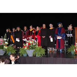 Faculty members stand onstage at School of Nursing convocation