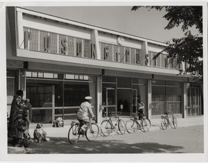 Exterior, post office at Maseru: bicycles and people in traditional dress in the street
