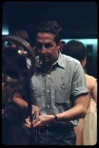 Artist Robert Rauschenberg, in front of a 16mm projector at a reception