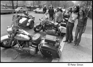 Elliot Blinder holding a puppy and Lacey Mason standing by parked Boston Police motorcycles