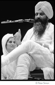 Yogi Bhajan on stage on the last night of the Kohoutek Celebration of Consciousness, with Hari Kaur Bird (?) beside him