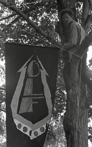 Gay liberation demonstration at Cambridge Common: man hanging Gay Liberation Front flag