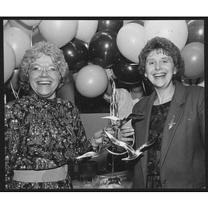 Women standing in front of balloons hold up an award