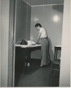 Physical therapist treating young woman on exam table