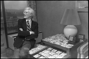 Andy Warhol seated by an array of polaroids at the Birmingham Museum of Art