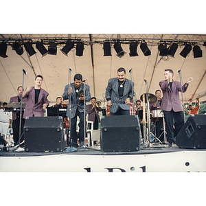 Four men dance and clap on stage at the Festival Puertorriqueño