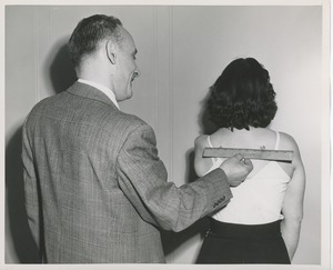 Man measuring woman's back for prosthesis fitting
