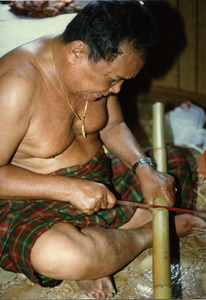 Cambodian basket maker Em Yung at home, cutting bamboo
