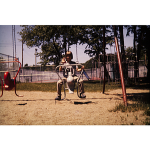 Child poses for photo on playground swing