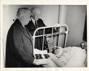 [Two men delivering a Hyde Park sweater to a boy in a hospital]