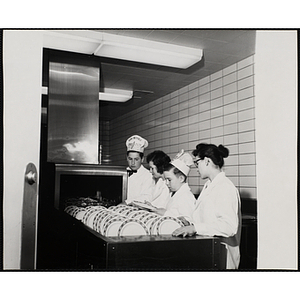 Two members of the Tom Pappas Chefs' Club operate a dishwasher with kitchen staff in a Howard Johnson's