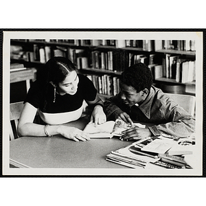 A woman tutors a boy at a table in a library