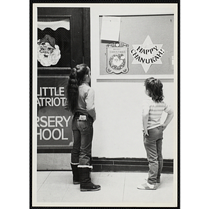 Two girls look at a holiday themed bulletin board