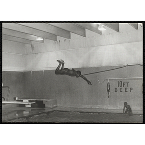A boy leaps from a diving board in a natorium pool