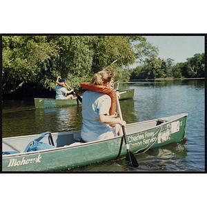 Girls paddle canoes on a lake
