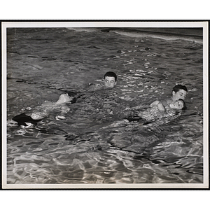 Teenage boys execute life saving drills in a natatorium pool