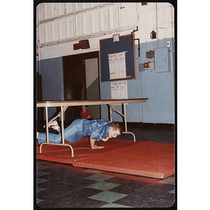 A boy crawls under a table at the Charlestown gymnasium