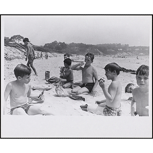 A group of boys have lunch on a beach