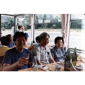Two men and a woman sit at a table while on a river cruise through Guilin, China