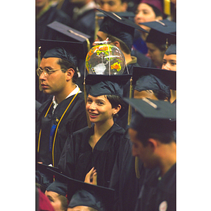 Student at commencement with globe beach ball tied to the mortarboard of her academic cap