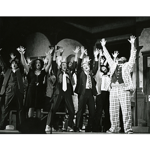 Cast of Northeastern University Department of Theatre's 1975 production of "Guys and Dolls" sing and hold their hands in the air during a musical number