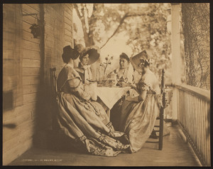 Four figures sitting at a table on a porch