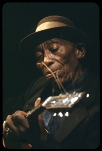 Mississippi John Hurt: studio portrait, seated, playing guitar