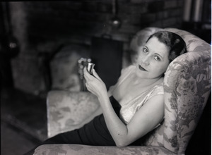 Mrs. Carl Miller (?) seated in a chair by the fireplace