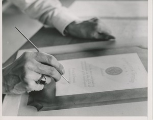A man finishes the lettering on the painted proof of the 1951 president's trophy