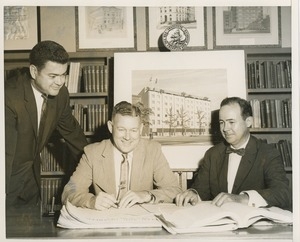 Willis C. Gorthy signing paperwork at a presentation of prospective building plans