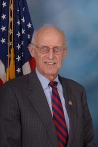 Congressman John W. Olver: half-length studio portrait in front of an American flag