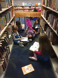 Some Daisy scouts catch up on their reading in the Children's Room while they wait for their meeting to begin.