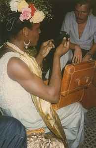 A Photograph of Marsha P. Johnson Opening a Present at Her Birthday Party, With a Leather Box on Her Lap