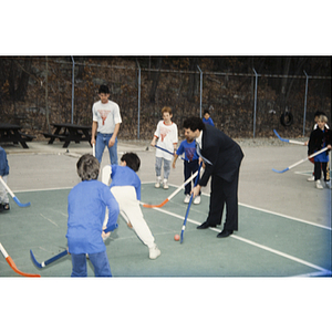 Field hockey game on an outdoor tennis court at the Eastern Middlesex Family YMCA