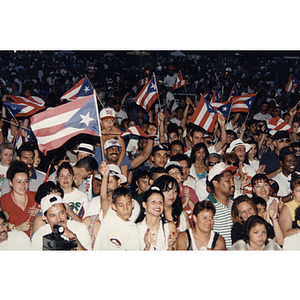 People wave Puerto Rican flags in a large crowd at the Festival Puertorriqueño