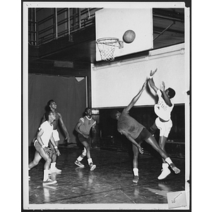 Young men playing basketball while one shoots for point