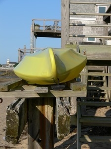 Plastic boat stored adjacent to a wooden deck