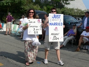 Parade marchers with signs celebrating same sex marriage reading 'Join us tomorrow 3 PM UU' and 'Just (about) married' : Provincetown Carnival parade