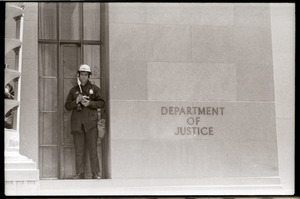 May Day demonstrations and street actions by the Justice Department: policeman standing by Department of Justice sign